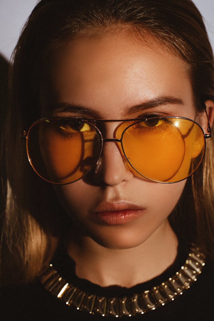 Close-up portrait of a fashionable woman wearing yellow sunglasses.